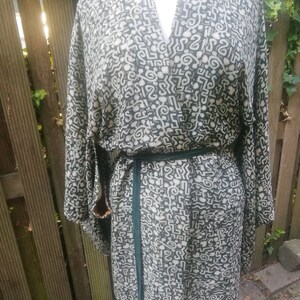 May include: A black and white patterned kimono with a green sash. The pattern is made up of abstract shapes and lines.