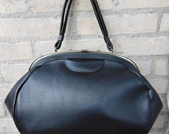 May include: A black vintage handbag with a gold clasp and two handles. The bag is made of a smooth, textured material.