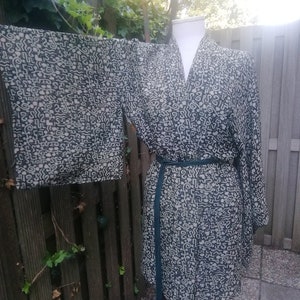 May include: A black and white patterned kimono robe with a green sash. The robe has a V-neck and long sleeves.