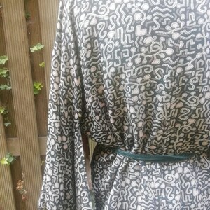 May include: A black and white patterned kimono with a green sash. The pattern is made up of abstract shapes and lines.
