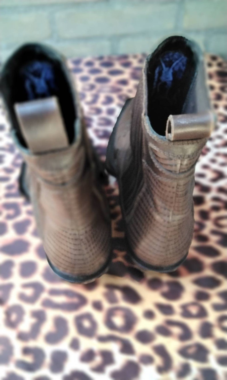 May include: A pair of brown leather ankle boots with a textured pattern. The boots have a pointed toe and a low heel.