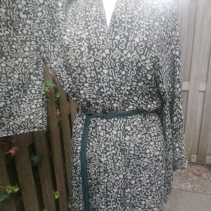 May include: A black and white patterned kimono robe with a green sash. The pattern is made up of abstract shapes and lines.