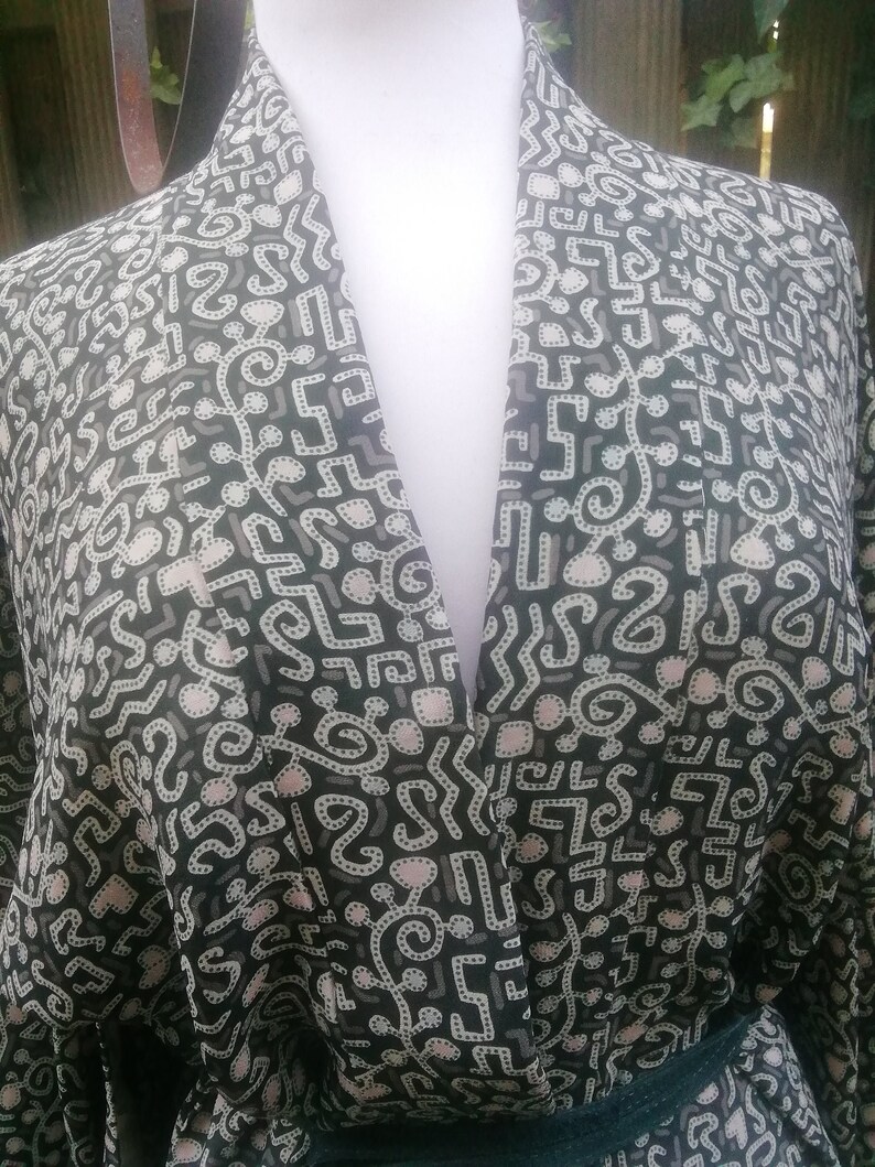 May include: A black and white patterned kimono with a V-neck and a dark green sash.