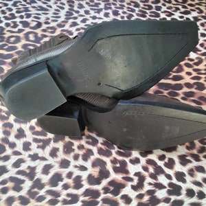 May include: A pair of brown leather cowboy boots with a pointed toe and a stacked heel. The boots have a textured leather upper and a rubber sole.