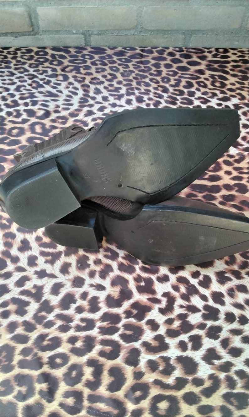 May include: A pair of brown leather cowboy boots with a pointed toe and a stacked heel. The boots have a textured leather upper and a rubber sole.