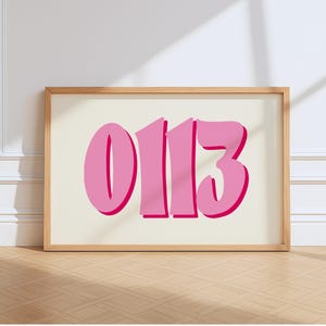Könnte beinhalten: Ein gerahmter Kunstdruck mit den Zahlen "0113" in einer fetten, blasenartigen Schriftart. Die Zahlen sind leuchtend rosa mit einer dunkleren rosa Umrandung, vor einem cremefarbenen Hintergrund. Der Rahmen ist helles Holz.