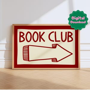 May include: A framed sign with the words "BOOK CLUB" in red, accompanied by a red arrow pointing right. The sign has a cream-colored background and a red border, set in a wooden frame. A green "Digital Download" sticker is in the upper right corner.
