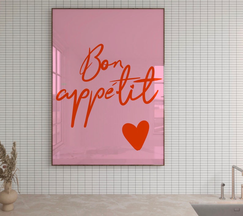 Puede incluir: Un p&oacute;ster enmarcado en rosa con el texto "Bon app&eacute;tit" en escritura cursiva roja. Un coraz&oacute;n rojo se encuentra en la esquina inferior derecha del p&oacute;ster.