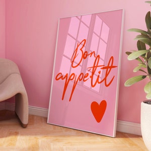 Puede incluir: P&oacute;ster enmarcado rosa con el texto "Bon app&eacute;tit" en letra roja con un coraz&oacute;n rojo debajo del texto.