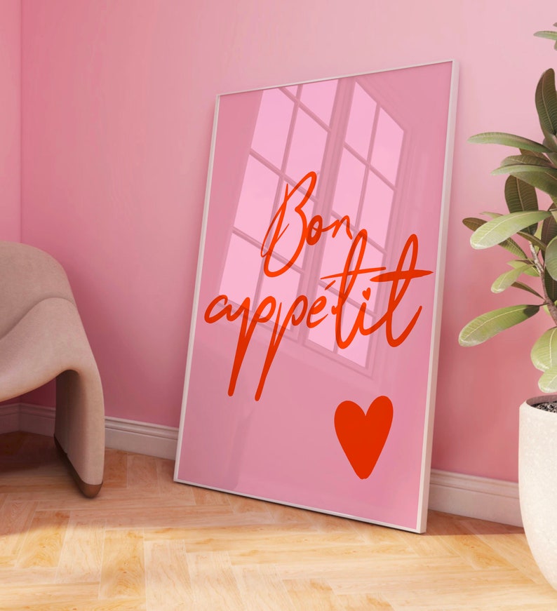 Puede incluir: P&oacute;ster enmarcado rosa con el texto "Bon app&eacute;tit" en letra roja con un coraz&oacute;n rojo debajo del texto.