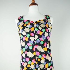 Könnte beinhalten: Schwarzes ärmelloses Kleid mit buntem Blättermuster. Das Kleid hat einen quadratischen Ausschnitt und einen knielangen Saum. Die Blätter sind in Rosa-, Gelb-, Grün-, Lila- und Beigetönen gehalten.