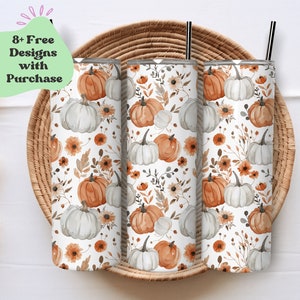 Peut inclure: Trois gobelets en acier inoxydable avec un fond blanc et un motif de citrouilles orange et grises, de feuilles et de fleurs. Les gobelets sont placés dans un panier en osier.