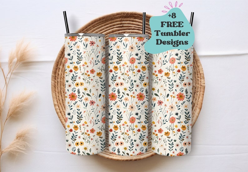 May include: Three stainless steel tumblers with a floral pattern in shades of orange, yellow, and pink on a white background. The tumblers are sitting in a woven basket. The text '+8 FREE Tumbler Designs' is in a speech bubble above the tumblers.