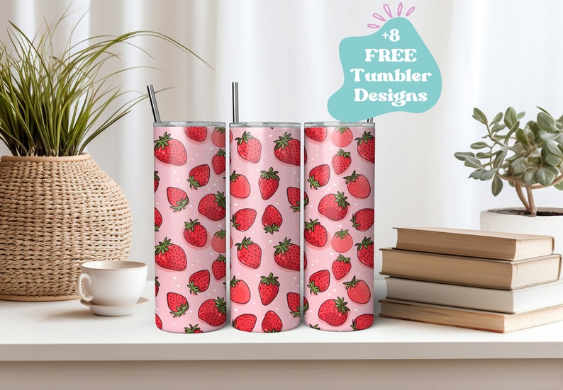 May include: Three stainless steel tumblers with a pink background and a pattern of red strawberries. Each tumbler has a black straw. The image also includes a text bubble that says "+8 FREE Tumbler Designs".