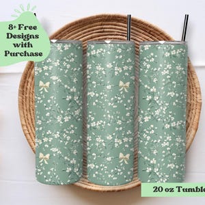 May include: Three 20 oz. tumbler wraps with a floral design in shades of green and white, accented with small bows. The tumblers are displayed on a woven basket. Text on the image reads "8+ Free Designs with Purchase" and "20 oz Tumbler Wrap."
