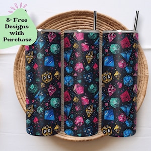 Pode incluir: Três canecas de aço inoxidável com fundo preto e um padrão de dados coloridos. Os dados são em tons de azul, rosa, verde e amarelo. Cada caneca tem uma palhinha preta e uma tampa prateada. As canecas são exibidas numa bandeja tecida.