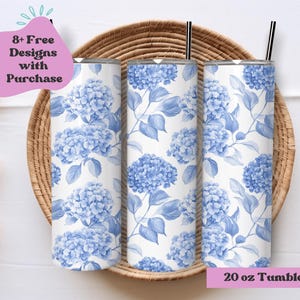 May include: Three 20 ounce stainless steel tumblers with a white background and blue floral pattern. The tumblers are displayed on a woven basket. The text "8+ Free Designs with Purchase" is in a pink box above the tumblers. The text "20 oz Tumbler Wrap" is in a pink box below the tumblers.