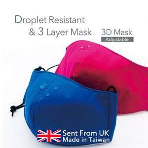 Op de afbeelding: Twee 3D-gezichtsmaskers, een blauwe en een roze, met waterdruppels erop. De maskers zijn gemaakt van waterafstotend materiaal en hebben verstelbare oorlussen. De tekst "Droplet Resistant & 3 Layer Mask 3D Mask Adjustable" is zichtbaar boven de maskers. De tekst "Sent From UK Made in Taiwan" is zichtbaar onder de maskers.