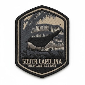 May include: A hexagonal embroidered patch featuring a black bird perched on a tree branch against a grey and beige background. The text SOUTH CAROLINA and THE PALMETTO STATE is stitched in beige at the bottom of the patch with a black border.