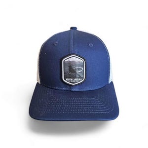 Może przedstawiać: Czapka trucker w kolorze granatowym i białym z naszywką z napisem "North Carolina The Tar Heel State".