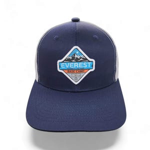 May include: A navy blue and white trucker hat with a white patch featuring a mountain range and the text "Everest South Base Camp 5,364 m".