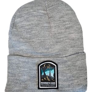 May include: Gray knitted beanie with a patch featuring a graphic of Mammoth Cave National Park in Kentucky.