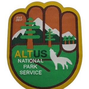 May include: A green and yellow embroidered patch with the text "ALTUS NATIONAL PARK SERVICE" and "EST 2017". The patch features a stylized hand with mountains, trees, and a wolf.