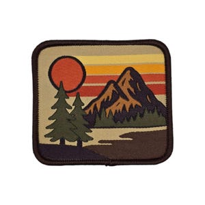 May include: A rectangular patch depicting a mountain scene at sunset. The design includes a red sun, green trees, and brown mountains against a striped background of orange, yellow, and brown. The patch has a brown border.