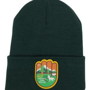 May include: A dark green knit beanie with a patch featuring a green, orange, and yellow design. The patch says "EST. 2017 ALTUS NATIONAL PARK SERVICE".