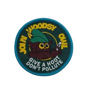 Può includere: Una toppa rotonda ricamata blu e verde con un gufo dei cartoni animati che tiene una lattina. Il testo recita "Join Woodsy Owl Give a Hoot Don't Pollute".