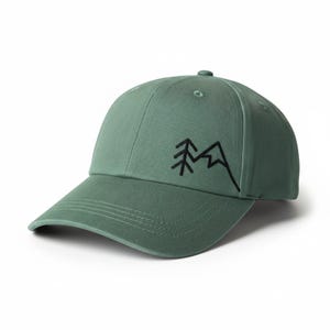 Könnte beinhalten: Eine salbeigrüne Baseballkappe mit gebogenem Schirm. Die Kappe hat ein schwarzes, gesticktes Berg- und Baumdesign auf der Vorderseite. Sie hat einen Knopf oben und einen verstellbaren Riemen.