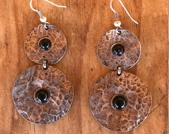 Earrings with two silver hammered like circles with black little stones.
