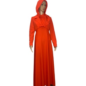 May include: A vibrant orange vintage dress with a matching hooded jacket. The dress features long sleeves and a floor-length skirt. The jacket has a collared neckline and a bow detail at the waist, creating a cohesive and stylish ensemble.