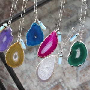 May include: Five silver necklaces with agate pendant charms and opalite crystal accents. The agate pendants are in shades of purple, blue, pink, yellow, and green.