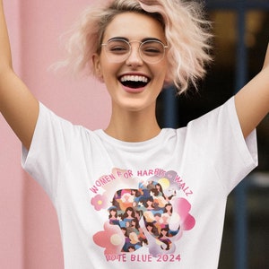 Peut inclure: Un t-shirt blanc avec un motif rose de visages de femmes formant une silhouette de femme. Le motif comprend le texte "Women for Harris & Walz" et "Vote Blue 2024".