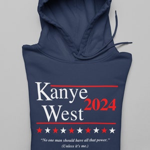以下が含まれることがあります： 紺色のフード付きスウェットシャツに、白と赤で「Kanye West 2024」の文字が書かれています。文字は赤い線と白い星の列で囲まれています。星の真下に「No one man should have all that power.」という文字が印刷され、その下に括弧で「(Unless it's me.)」とあります。