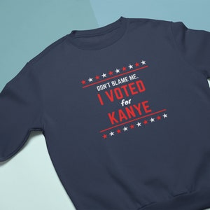 May include: A navy blue sweatshirt with the text "DON'T BLAME ME. I VOTED for KANYE" in red and white stars on the front.