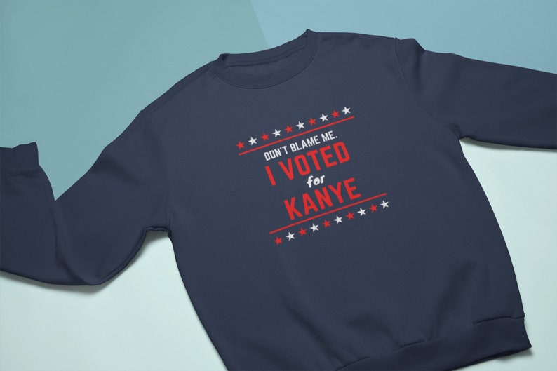 May include: A navy blue sweatshirt with the text "DON'T BLAME ME. I VOTED for KANYE" in red and white stars on the front.
