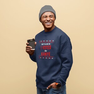 May include: A navy blue sweatshirt with a red and white graphic that says "Don't blame me. I voted for Kanye." The sweatshirt has a row of white stars above and below the text.