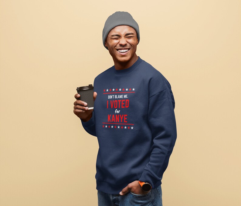 May include: A navy blue sweatshirt with a red and white graphic that says "Don't blame me. I voted for Kanye." The sweatshirt has a row of white stars above and below the text.