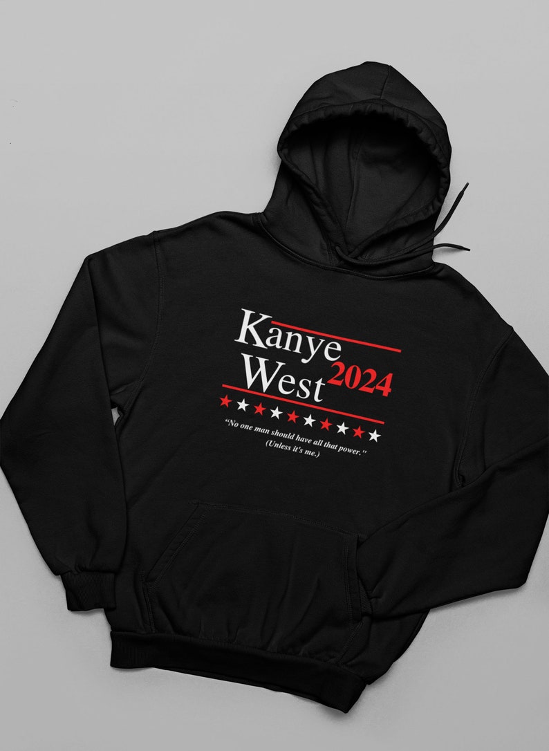 以下が含まれることがあります： 「Kanye West 2024」と「No one man should have all that power. (Unless it's me.)」という白いプリントが施された黒いフード付きスウェットシャツ。テキストの両側に赤い星が5つずつあります。