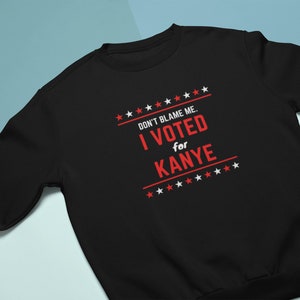May include: Black sweatshirt with white stars and the text "DON'T BLAME ME. I VOTED for KANYE" in red.
