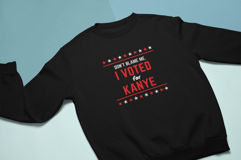 May include: Black sweatshirt with white stars and the text "DON'T BLAME ME. I VOTED for KANYE" in red.