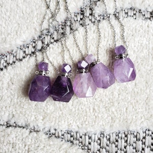 May include: Six amethyst crystal bottle necklaces with silver chains. The bottles are faceted and have silver stoppers.