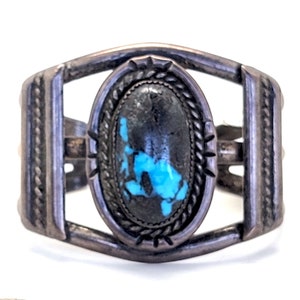 May include: A silver bracelet with a turquoise stone set in a silver bezel. The bracelet is decorated with a rope design and has a simple, elegant style.
