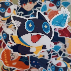 Op de afbeelding: Een zwart-witte cartoonkat met een gele sjaal en blauwe ogen. De kat houdt een blauwe diamant in zijn bek. De kat wordt omringd door andere stickers, waaronder een personage met zwart haar en rode ogen.