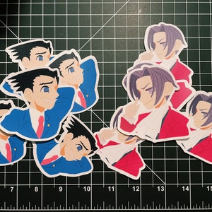 May include: A set of six stickers featuring anime characters. The stickers are printed on white paper with a glossy finish. The characters are depicted in various poses and expressions. The stickers are perfect for adding a touch of personality to laptops, water bottles, or other belongings.