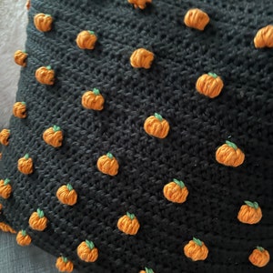 Pu&ograve; includere: Cuscino nero all'uncinetto con decorazioni a forma di zucca arancione in rilievo con gambi verdi. Bordo arancione. Perfetto per l'autunno o Halloween.