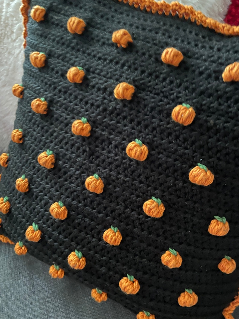 Pu&ograve; includere: Cuscino nero all'uncinetto con decorazioni a forma di zucca arancione in rilievo con gambi verdi. Bordo arancione. Perfetto per l'autunno o Halloween.
