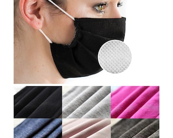 Puede incluir: Una mascarilla facial negra con una capa de filtro blanca. La mascarilla está hecha de un tejido suave y transpirable. La imagen también muestra primeros planos de diferentes colores de tejido: negro, gris, rosa, azul, beige y gris.
